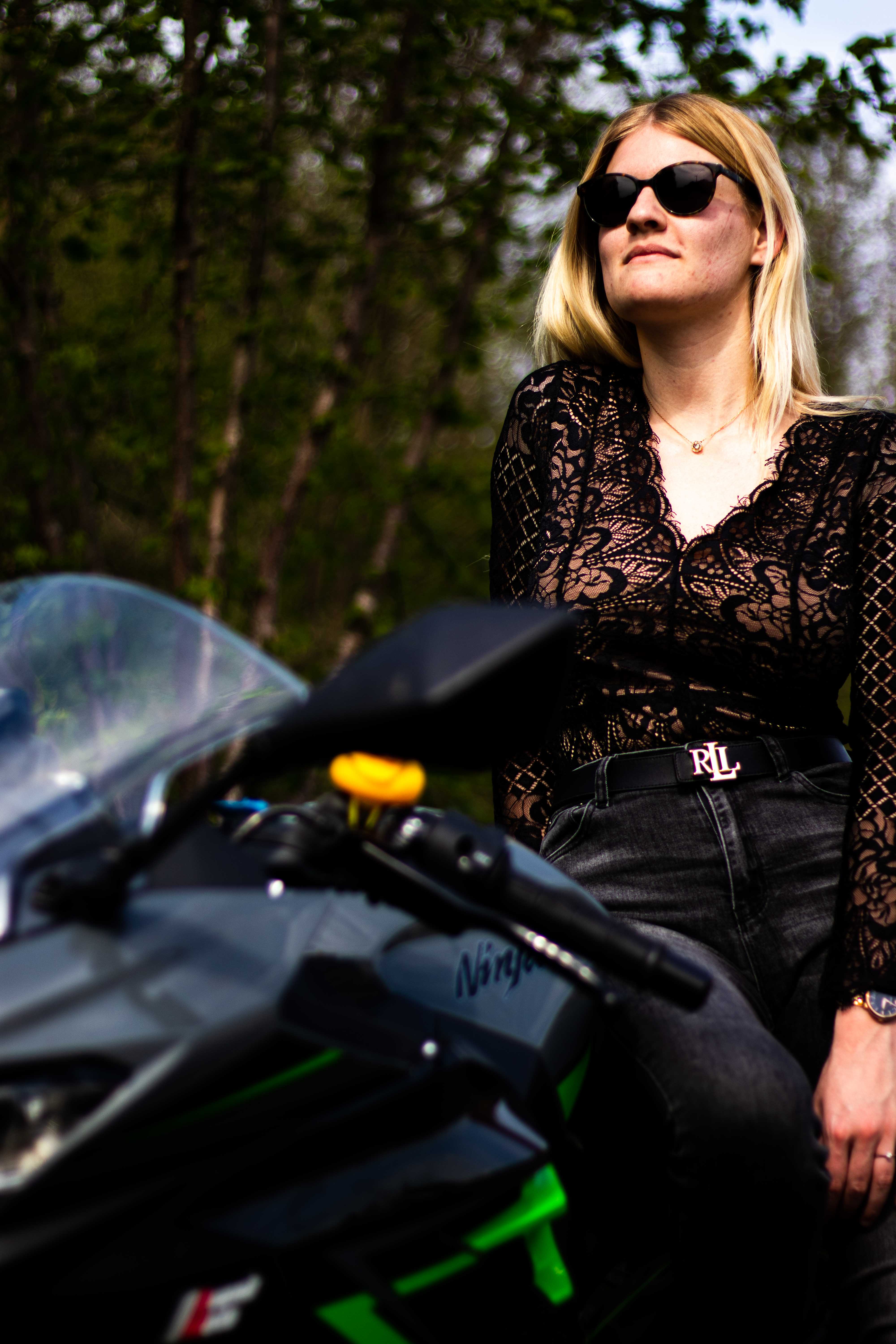 Photo d'une femmme assise sur une moto avec le regard hors champ en vue contre-plongé